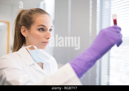 Scientist in lab examining blood sample Stock Photo