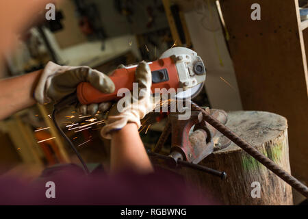 Craftswoman using angle grinder in her workshop Stock Photo
