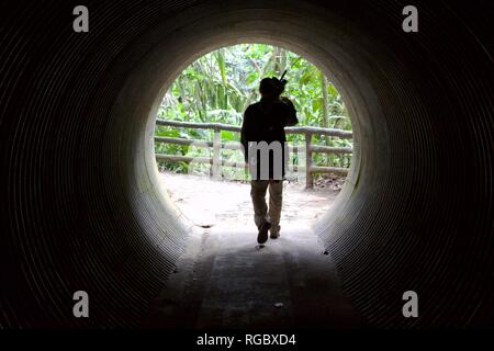 Silhouette of a man coming out of a dark tunnel emerging into the light Stock Photo