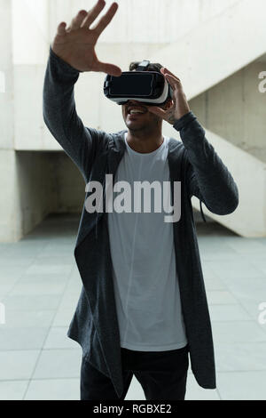 Young man wearing Virtual Reality Glasses raising his hand Stock Photo