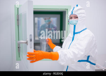 Lab technician wearing cleanroom overall at material sluice
