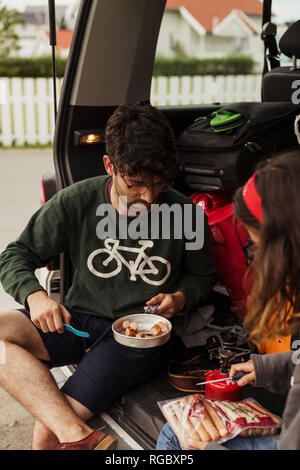 Young couple preparing sausages on a camping stove Stock Photo