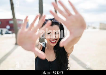 Portrait of young woman with nose piercing looking through her hands Stock Photo