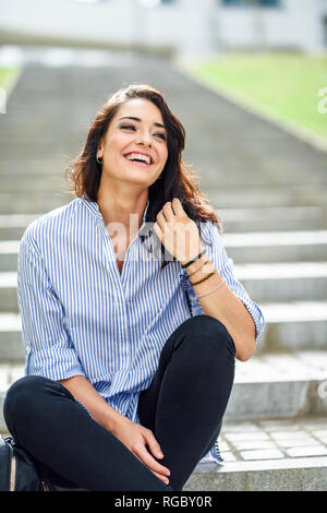 Portrait of laughing student sitting on stairs Stock Photo
