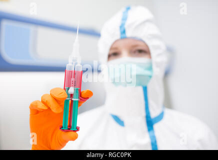 Lab technician wearing cleanroom overall holding syringe