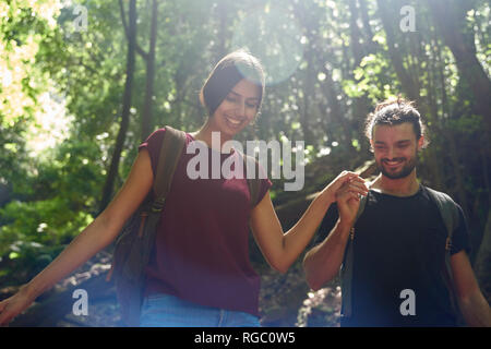 Spain, Canary Islands, La Palma, smiling couple walking hand in hand through a forest Stock Photo
