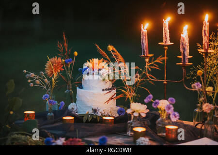 Wedding cake on table with candles outdoors Stock Photo