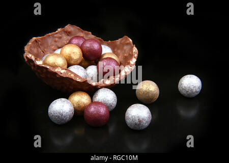 Modern sophistocated chocolate gold, silver & broze easter eggs, against a black background. Stock Photo