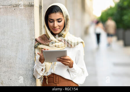 Spain, Granada, young muslim woman wearing hijab using tablet outdoor Stock Photo