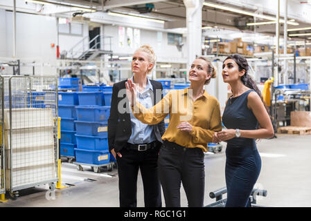 Three women talking in modern factory Stock Photo