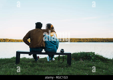 A couple sitting on a bench looking out at the ocean Stock Photo - Alamy