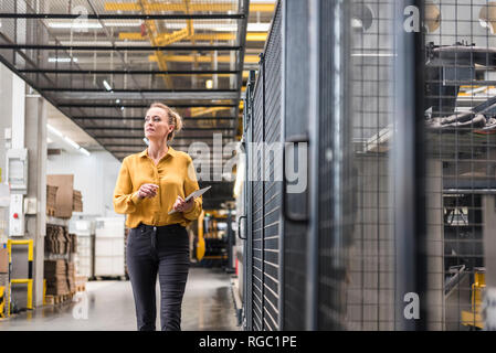 Woman with tablet walking in factory shop floor Stock Photo