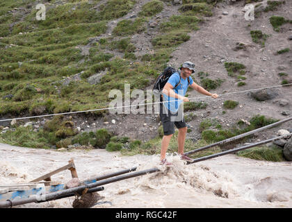Russia, Caucasus, Mountaineer crossing river in Upper Baksan Valley Stock Photo