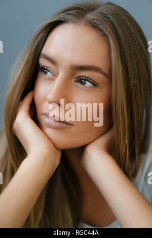 Portrait of daydreaming young woman  with head in hands Stock Photo