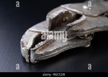 An old special clamping key for a plumber. Tools for home repairs. Dark background. Stock Photo