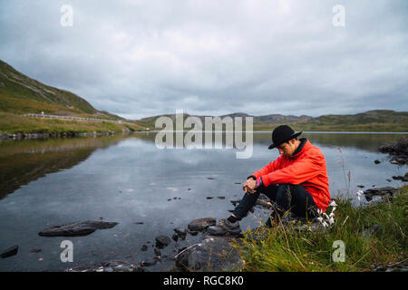 Young man sitting sad at a lake Stock Photo
