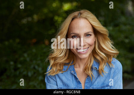 Portrait of smiling blond woman outdoors Stock Photo