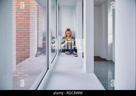 Student sitting at the window in hallway learning Stock Photo