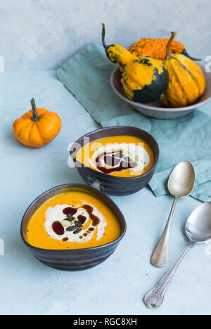 Two bowls of homemade Hokkaido pumpkin soup garnished with cream, pumpkin seed oil and pumpkin seed Stock Photo