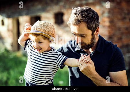 Father assisting his little son in balancing on a fence Stock Photo