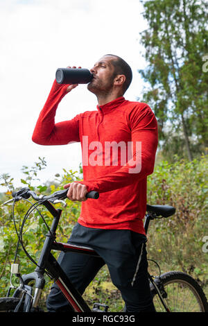 Athlete mountainbiking in nature, taking a break, drinking water Stock Photo