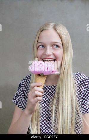Portrait of blond girl testing flower head of pink peony in ice cream cone Stock Photo