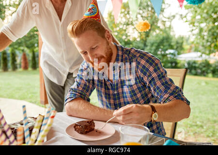 Man eating cake on a birthday garden party Stock Photo
