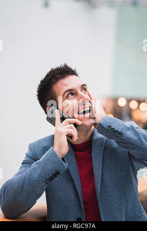 Businessman in lobby of a modern building, using smartphone Stock Photo