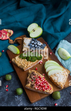Bread slices with various toppings on wooden board Stock Photo