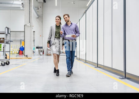 Businessman and woman walking in company, discussing new strategies Stock Photo