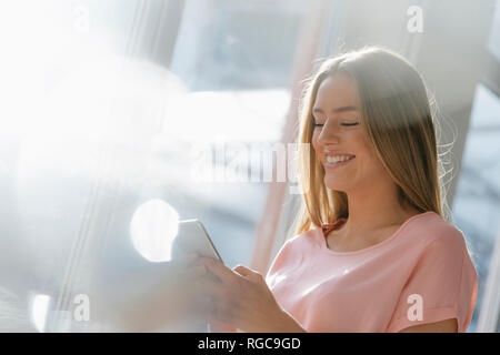 Portrait of laughing young woman looking at cell phone Stock Photo