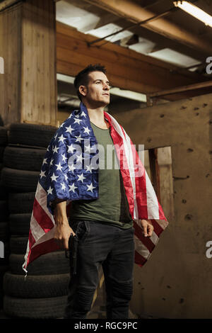 Man wearing American flag holding a gun Stock Photo
