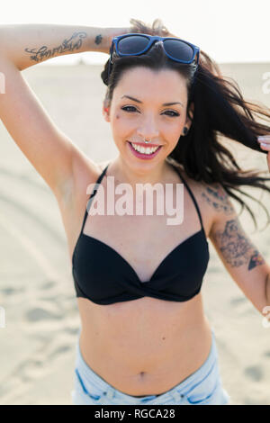Portrait of tattooed young woman with nose piercing and tattoo on the beach