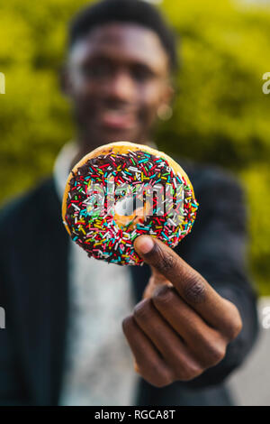 Young black man holding a chocolate cookie Stock Photo