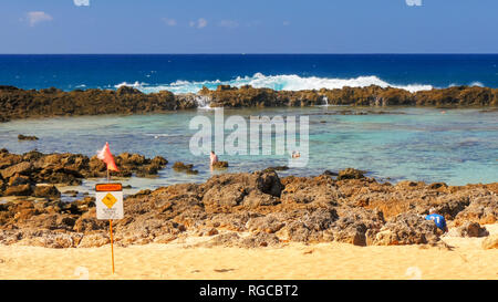 a wave breaks onto the rocks and pours into the tide pool at shark cove on the north shore of oahu Stock Photo