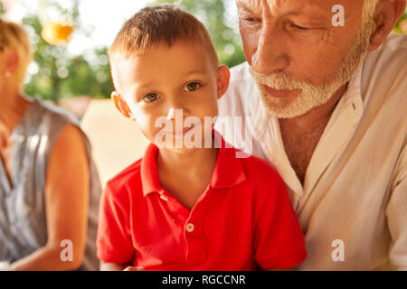 Portrait of smiling boy on grandfather's lap Stock Photo