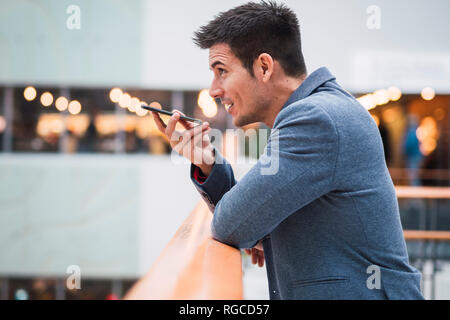 Businessman in lobby of a modern building, using smartphone Stock Photo