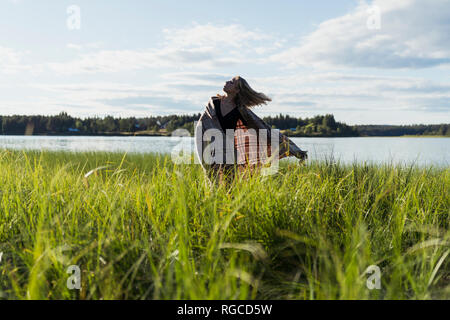 Finland, Lapland, woman with a blanket at the lakeside Stock Photo