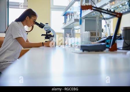 Young woman using microscope in laboratory Stock Photo