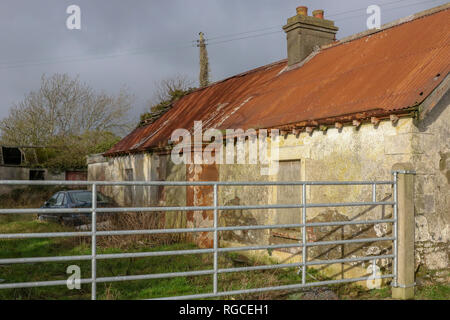 Entrance to abandoned farm cottage with old car in farmyard. Stock Photo
