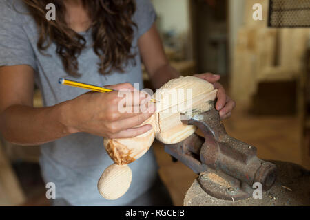 Craftswoman working with pencil on a piece of wood in her workshop Stock Photo