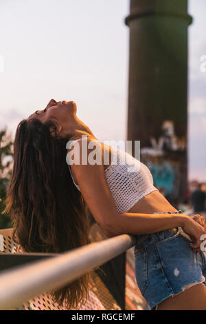 Beautiful young woman with long brown hair leaning back outdoors Stock Photo