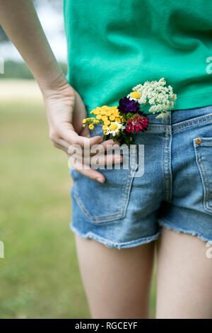 Flowers in pocket of girl's jeans shorts Stock Photo