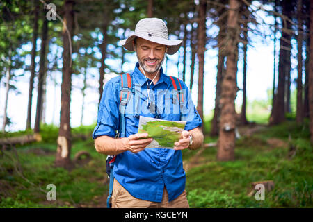 Smiling man looking at map during a hike in the forest Stock Photo