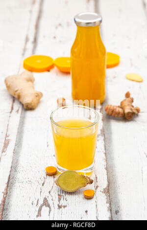 Ginger shot with orange and curcuma on white wood Stock Photo
