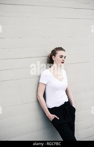 Portrait of cool young woman leaning against wall Stock Photo