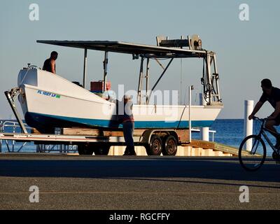 Men securing clamming boat on trailer after hauling it out of the water at Cedar Key, Florida, USA. Stock Photo