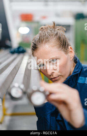 Young woman working as a skilled worker in a high tech company, checking steel rods Stock Photo