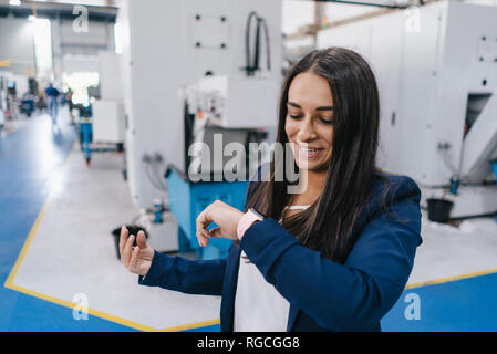 Confident woman working in high tech enterprise, using smartwatch for a call Stock Photo