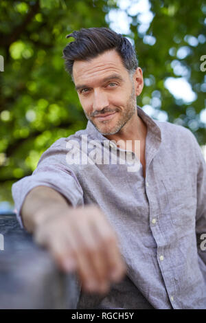 Portrait of smiling mature man leaning on a wall Stock Photo
